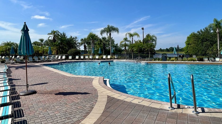 A resort swimming pool lined with palm trees and umbrellas