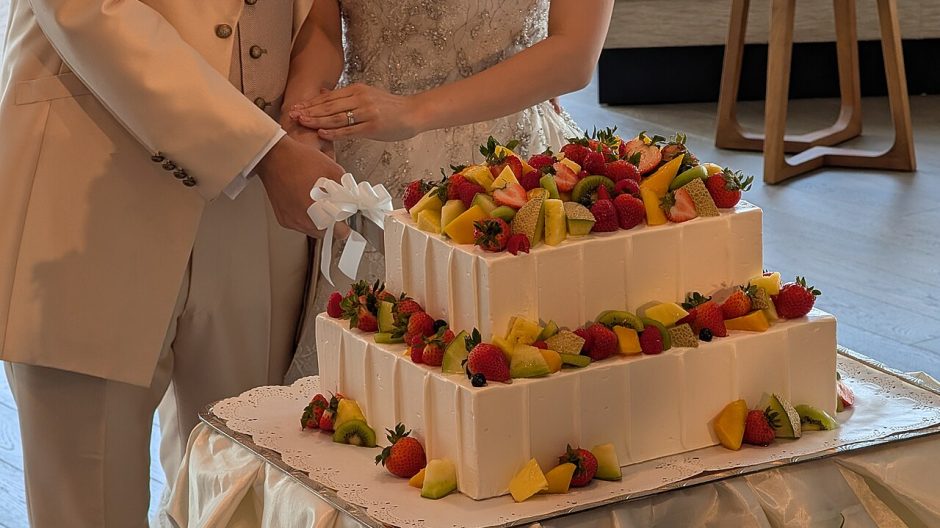 A couple cutting a fruit-topped wedding cake