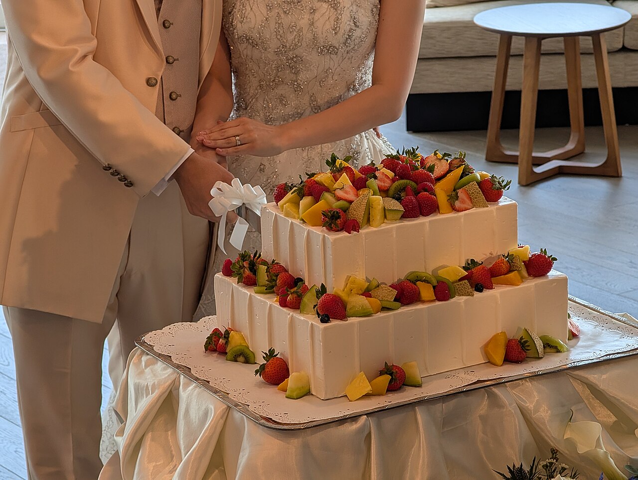 A couple cutting a fruit-topped wedding cake