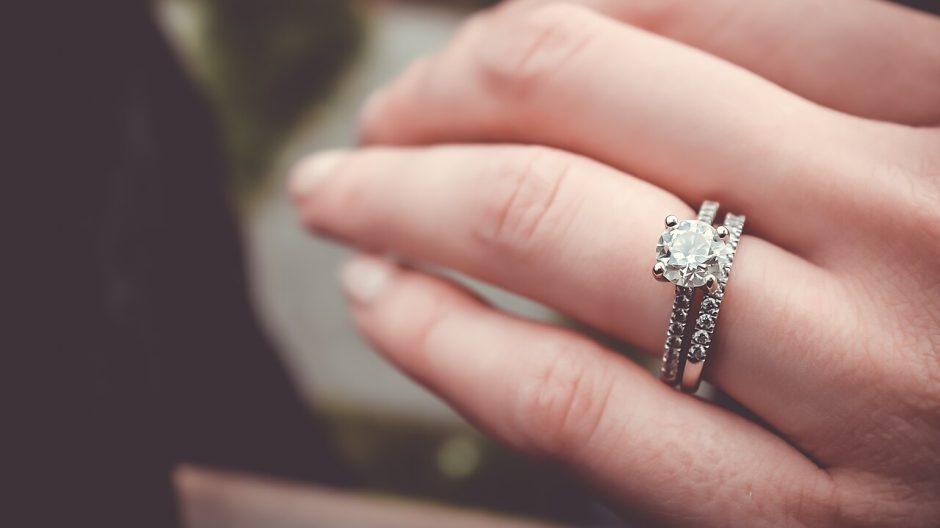 Close-up of a hand wearing a diamond engagement ring and wedding band