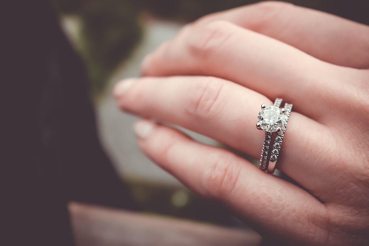 Close-up of a hand wearing a diamond engagement ring and wedding band